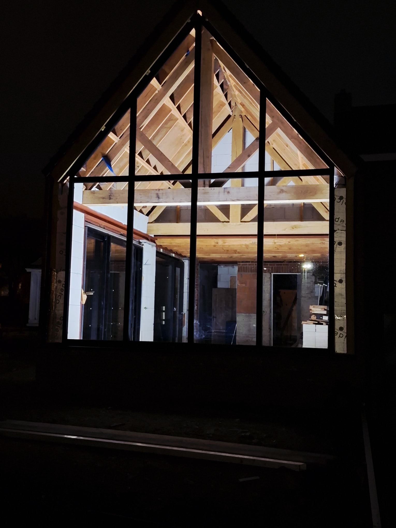 Glazen kopgevel met zichtbare houtstructuur bij avond